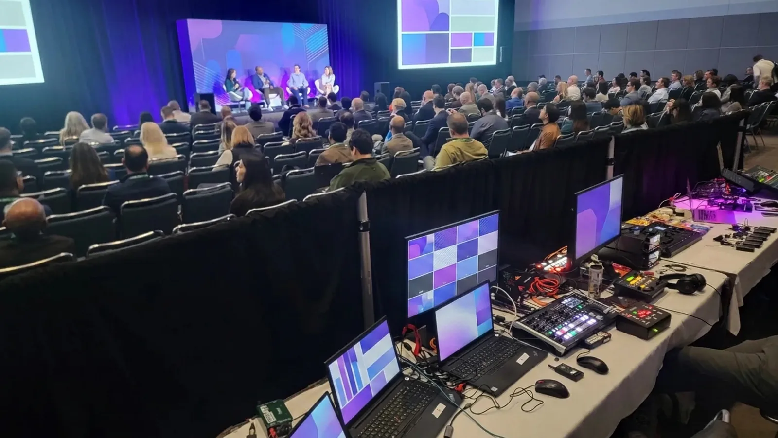 Conference general session with dual screens and a live show control desk